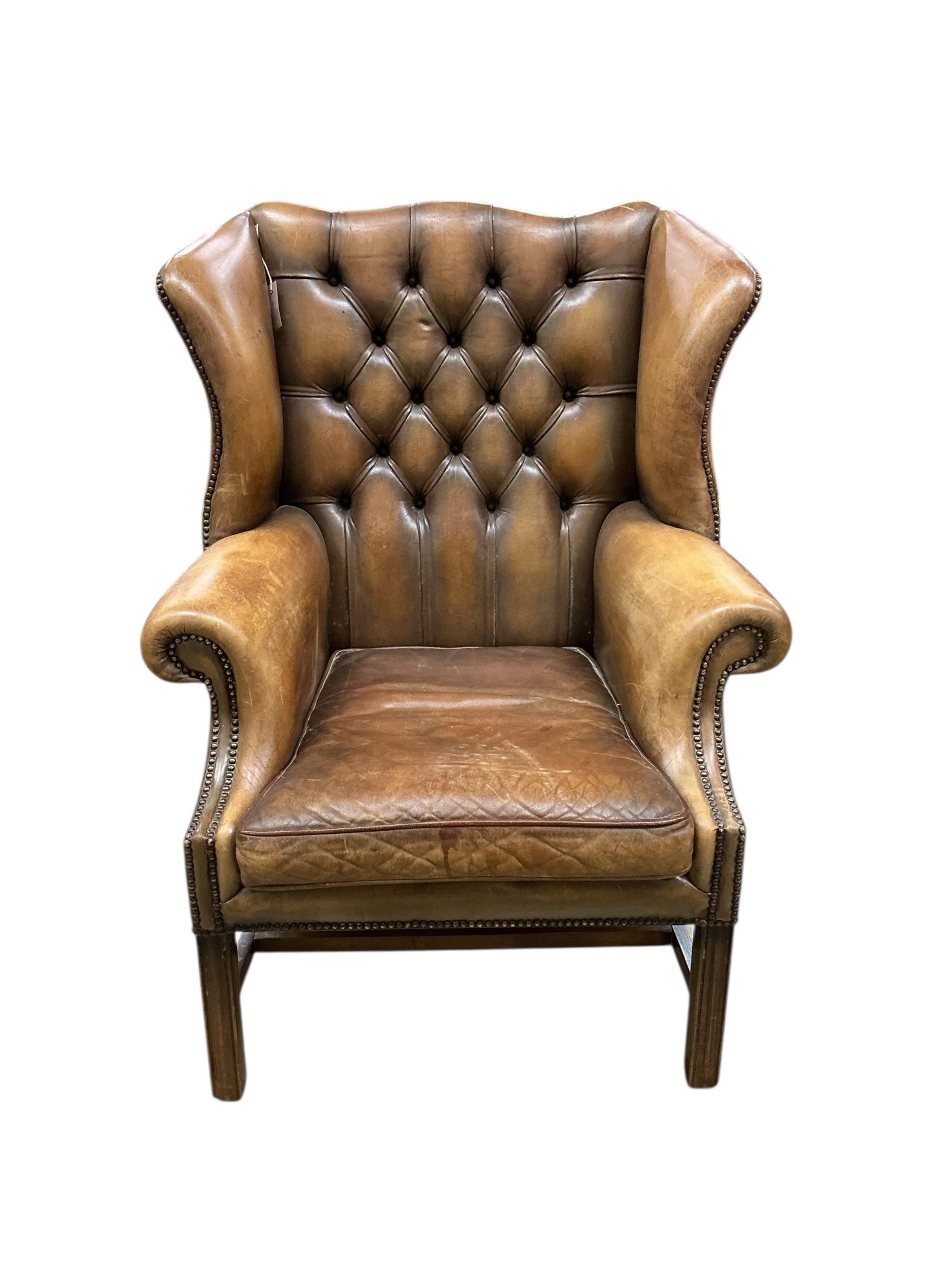 A reproduction George III style buttoned tan leather wing armchair, width 84cm, depth 74cm, height 110cm